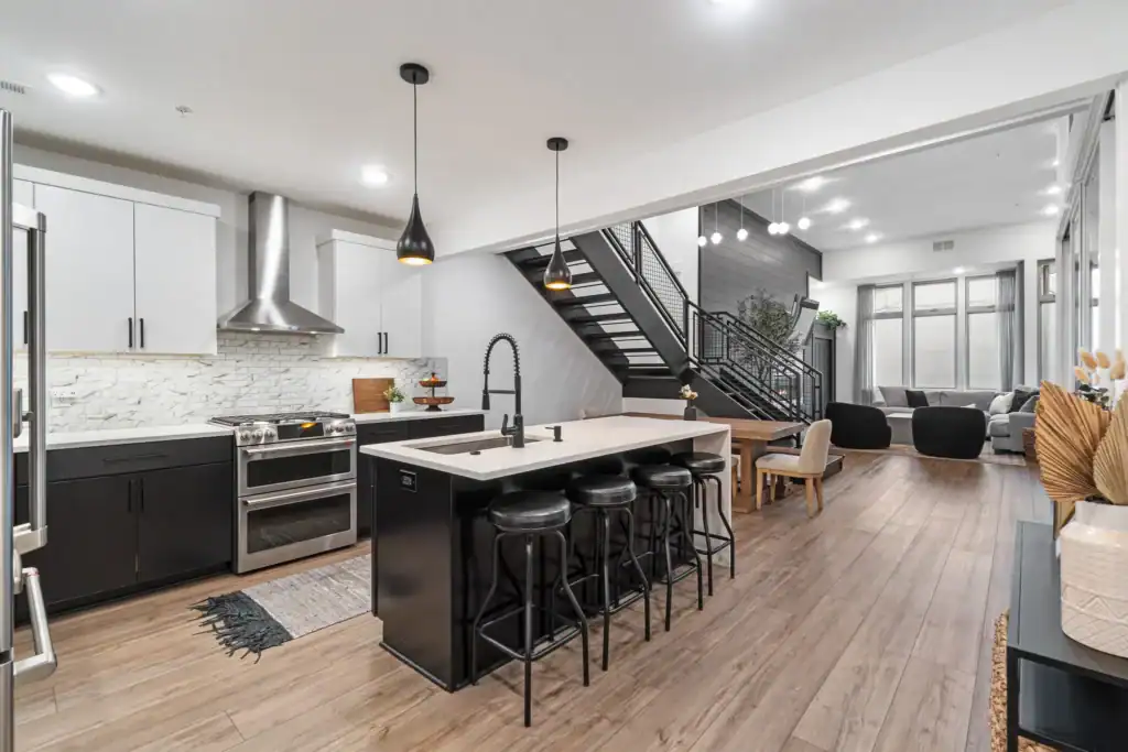 Open concept kitchen remodel in St. Petersburg Florida with black and white cabinets, waterfall island, and modern lighting